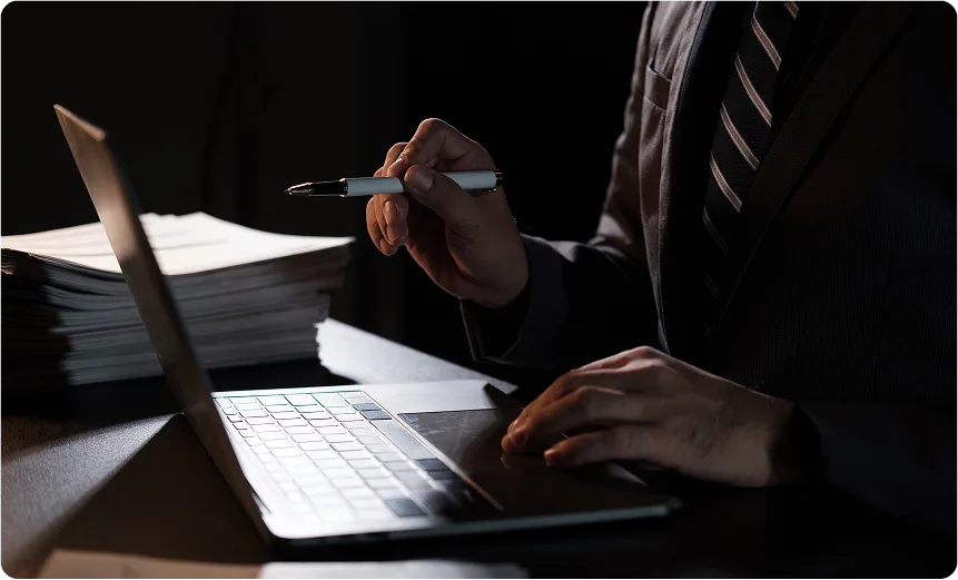 Businessman working on laptop with documents at night