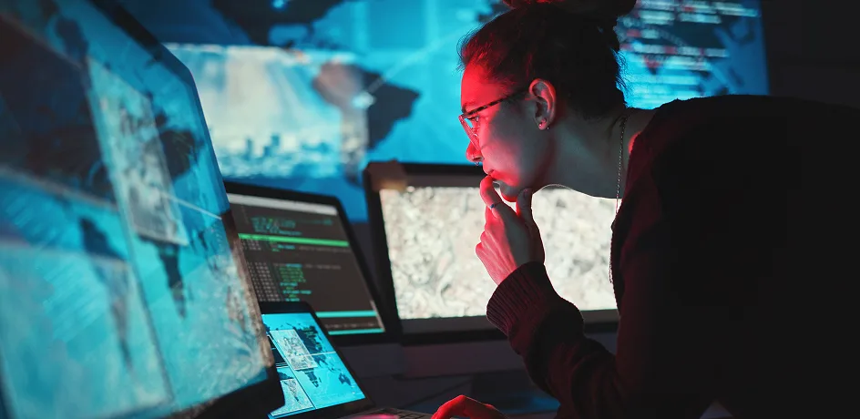 Cybersecurity analyst monitoring multiple screens with system logs and threat data in security operations center