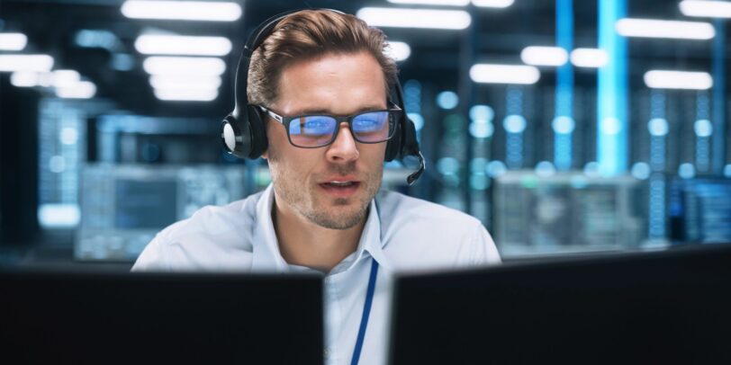 IT support specialist wearing a headset working in a modern operation center.